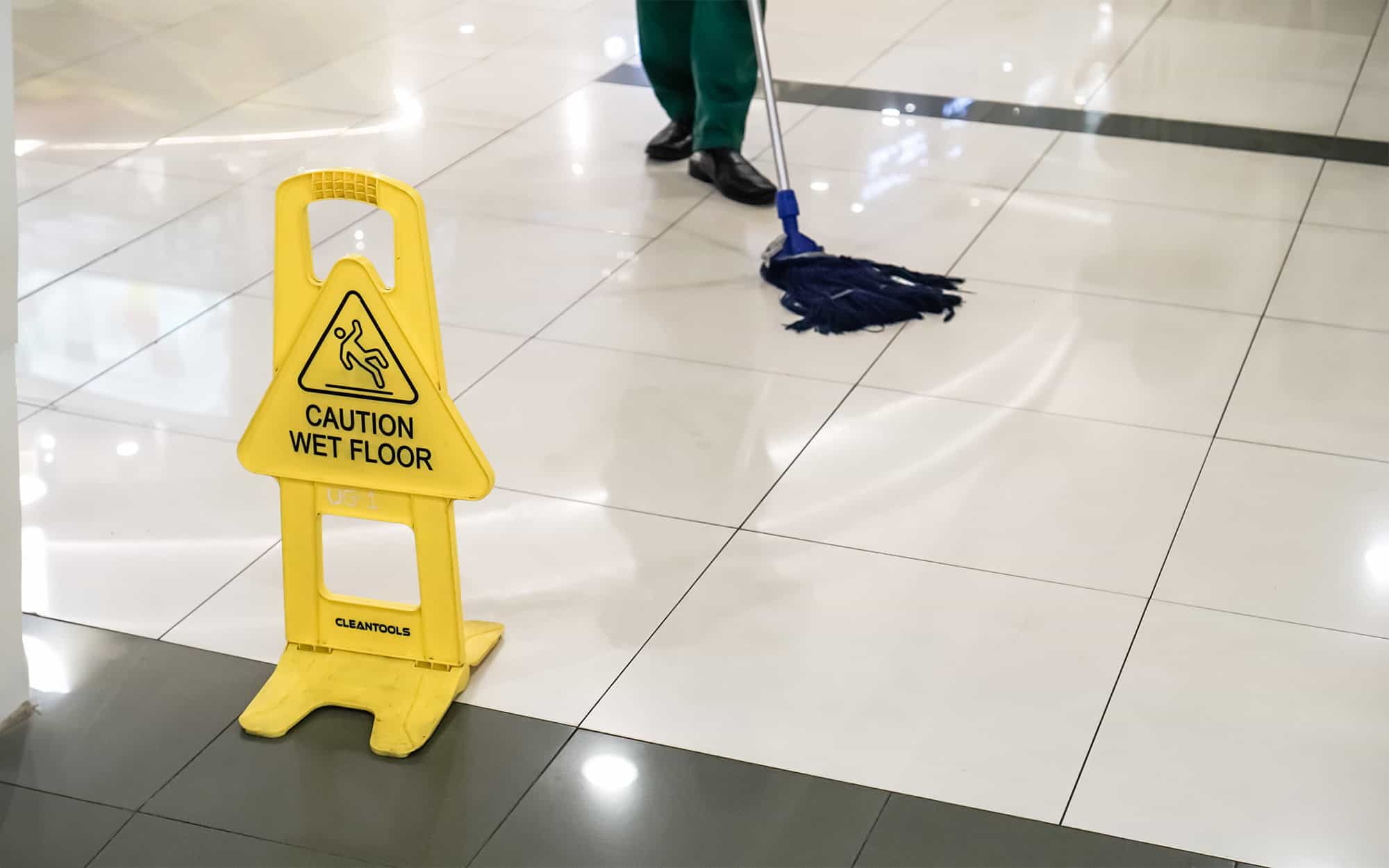 Side View Of A Lobby Being Mopped With Yellow Wet Floor Sign