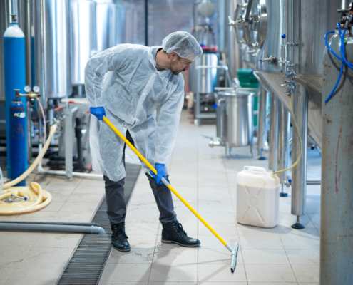 Worker Cleaning Floor In Industrial Facility